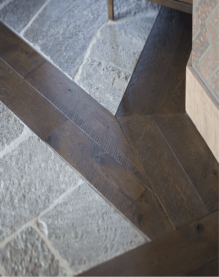 Dark hardwood flooring integrated with stone flooring transitions