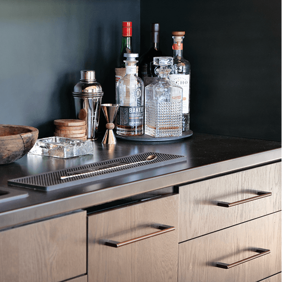Bar counter with custom white oak cabinetry and an integrated stainless drink rail
